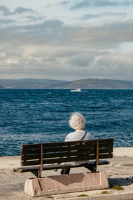 坐在海边长凳上的老奶奶背影图片下载