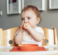 婴儿坐在宝宝椅上吃东西图片下载