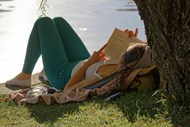 美女躺在湖岸边看书高清图片