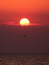 黄昏落日余晖海面飞行的飞机图片下载