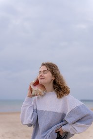 站在海滩手持海螺听海的女生精美图片