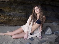 坐在沙滩岩洞里的性感美女精美图片