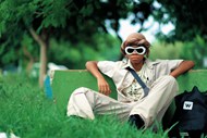 坐在草地上的戴墨镜男孩高清图片