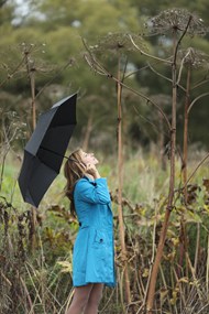撑着黑色雨伞的蓝色风衣美女图片
