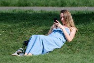 躺在绿色草地上看手机的美女高清图片